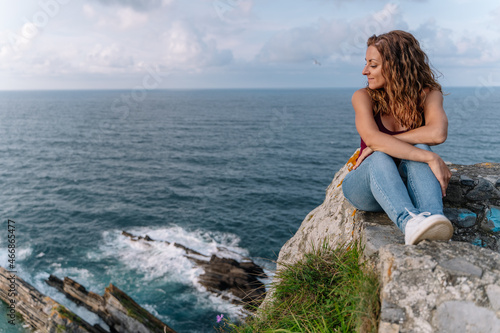 Panoramic view of woman on holidays in Asturias. Horizontal view of cheerful woman isolated in blue sea in the background. Travel on holidays and people concept.