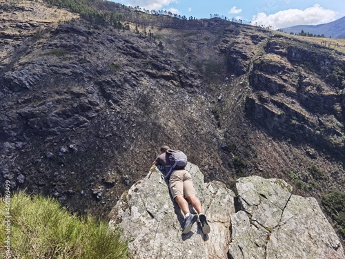 Rapaz turista na montanha a olhar o penhasco que é bem fundo photo