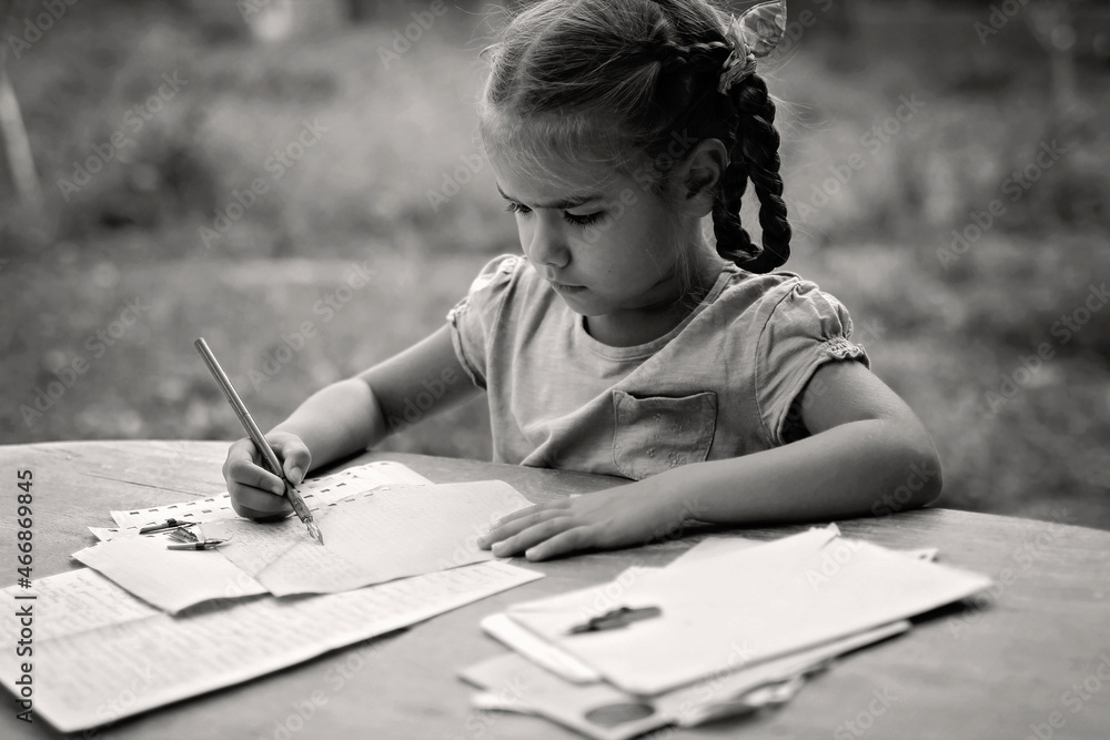 A little girl writing a letter with ink pen, old envelopes, ink pen and ...