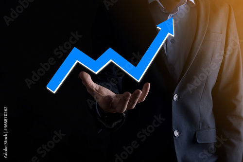 Businessman man holding a graph with positive profits growth. plan graph growth and increase of chart positive indicators in his business.more profitable and growing.