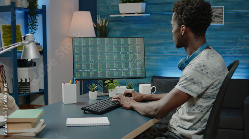 Black business man looking at stock market analysis for crypto currency on monitor. African american broker analyzing financial charts for global investment with exchange money on computer