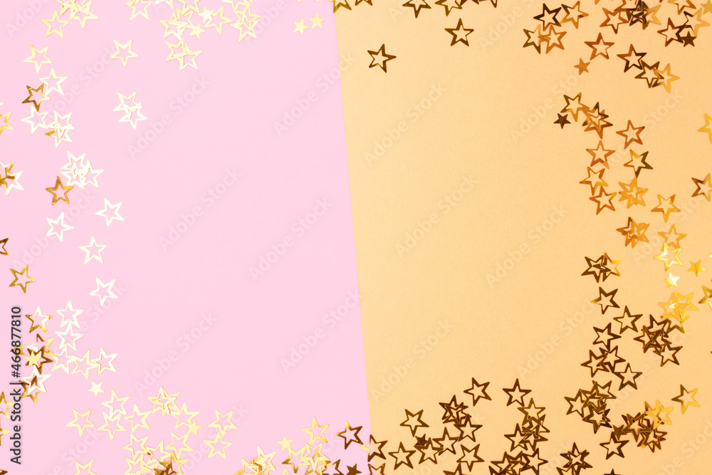 Border frame made of stars confetti on a pink and gold pastel background.