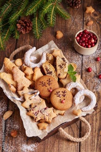 Box with variety of Christmas cookies: gingerbread deers, stars with cranberries, Christmas trees with brown sugar, Biscotti cantucci with oranges, almonds and chocolate, horseshoe with sugar powder