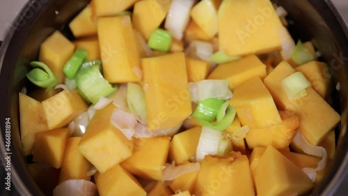 Pumpkin soup preparation. Saucepan with chopped celery and cubed pumpkin