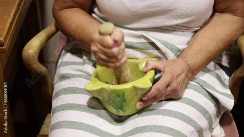 Woman pestling garlic and cumin seeds in a mortar