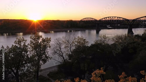 Flying towards the sun setting over North Dakota along the Missouri River with historic old railway bridge spanning the water.