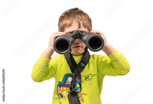The boy looks through binoculars. Photo in the studio.
