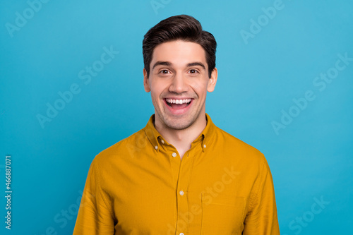 Photo of excited funky young guy dressed yellow shirt smiling open mouth isolated blue color background