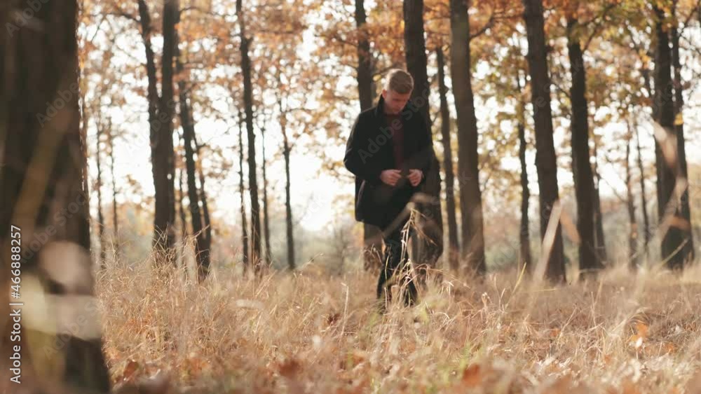 Portrait of handsome man in black coat walking in autumn forest on sunny day Portrait of handsome man in black coat walking in autumn forest on sunny day
