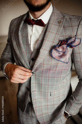 Boutonniere on the jacket. bard bow tie for the groom. Wedding suit in a cage. A burgundy handkerchief in a jacket pocket