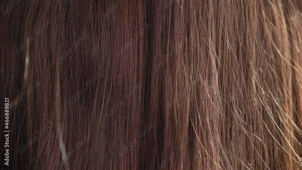 female hand combing long beautiful healthy flowing brown hair close-up, sun rays shine on texture female hand combing long beautiful healthy flowing brown hair close-up, sun rays shine on texture