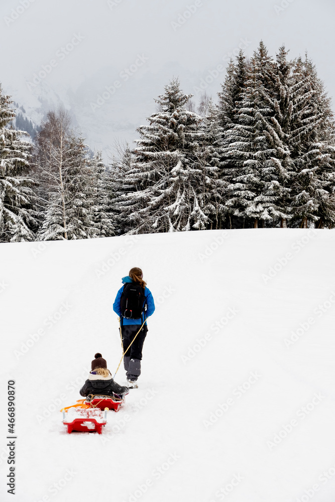 Randonneuse dans la neige tirant un enfant sur une luge