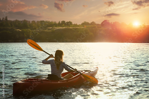 Woman kayaking on river at sunset, back view. Summer activity © New Africa