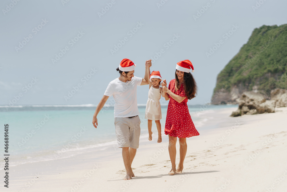 Happy family of three in Christmas Hats during tropical vacation, have fun, enjoy holidays together Happy family of three in Christmas Hats during tropical vacation, have fun, enjoy holidays together