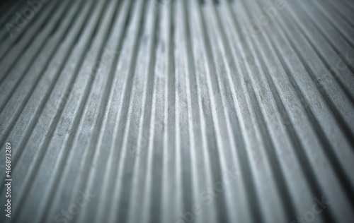 strong lighting and contrast on lines formed on a silver rustic metal fence outdoors  in the backyard