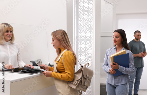 Foto Woman with money and other people in line at cash department window