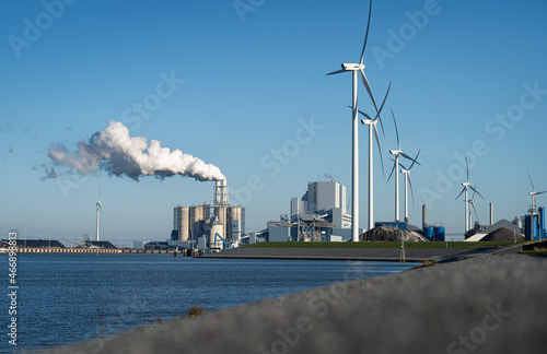 Fossil fuel (coal) power station and wind turbines in the Eemshaven generating power. Energy transition concept.