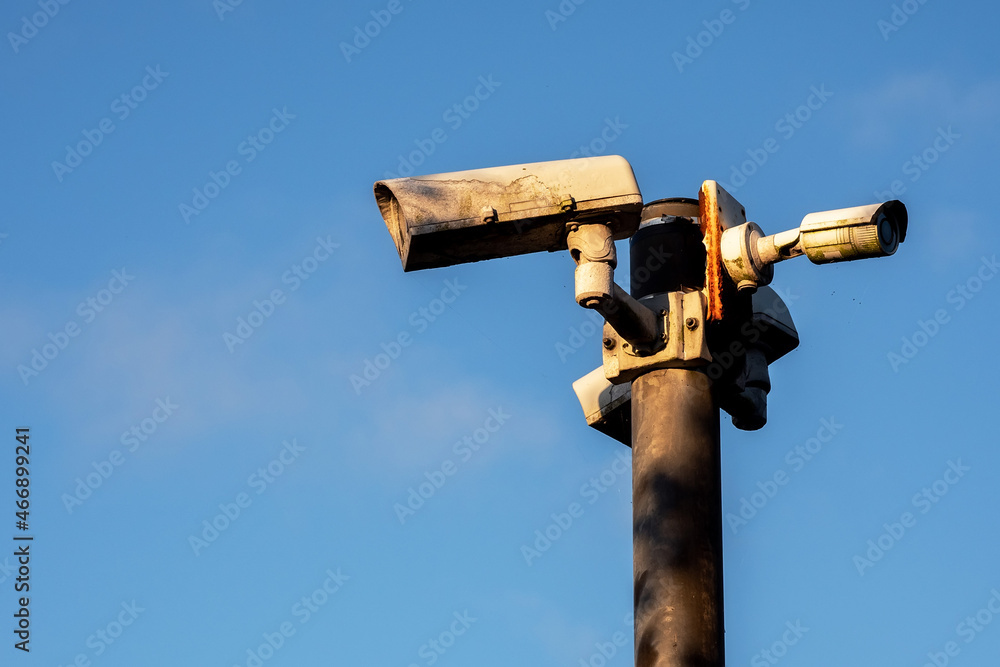 Old weathered CCTV digital cameras on a metal pole against clear blue sky. Copy space. Security and safety concept Old weathered CCTV digital cameras on a metal pole against clear blue sky. Copy space. Security and safety concept