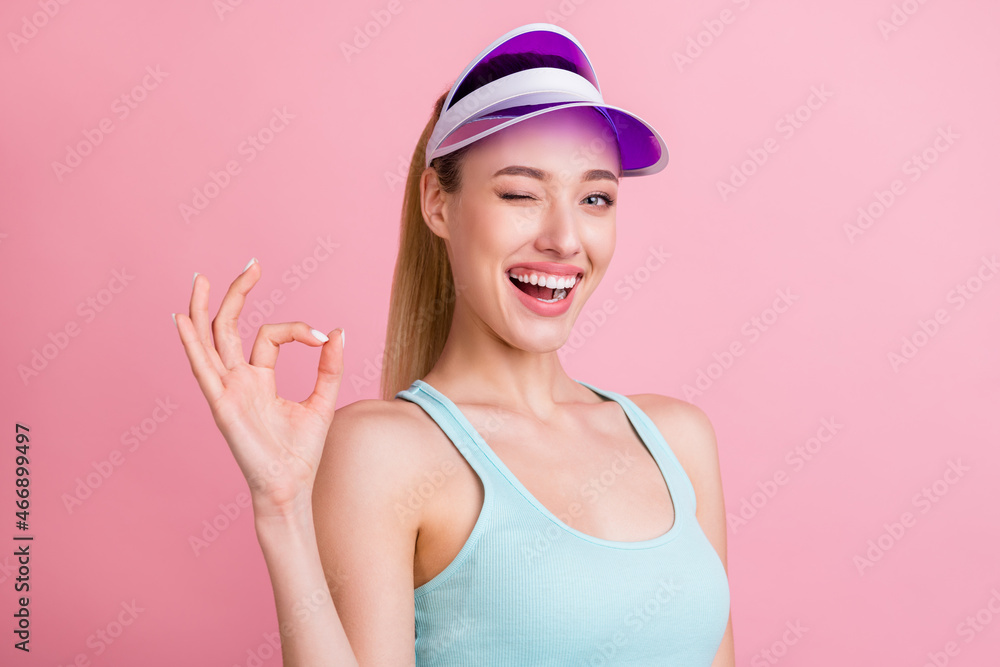 Photo of funky blond millennial lady show okey wear blue top visor isolated on pink color background Photo of funky blond millennial lady show okey wear blue top visor isolated on pink color background