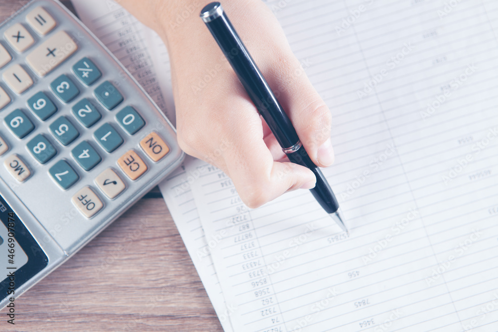young woman counts on calculator and makes notes on papers young woman counts on calculator and makes notes on papers