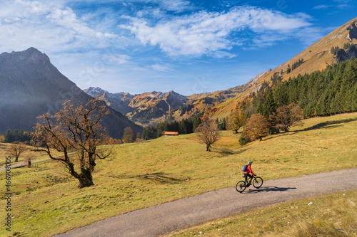 pretty woman riding her electric mountain bike in the mountains of Hinterstein Valley in the upper Allgaeu on warm autumn day, Bavaria, Germany © Uwe