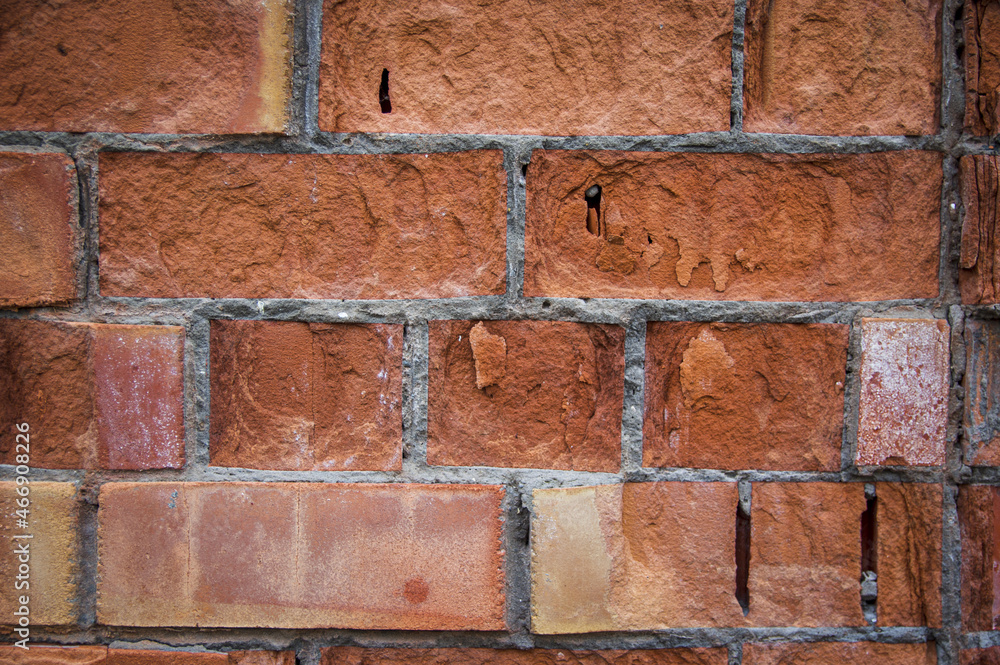 Fototapeta premium Grey white black red orange old vintage brick wall background. Rustic cemented dark brick house wall texture with grunge surface. Shabby Building Facade With Damaged Plaster. Aged weathered exterior