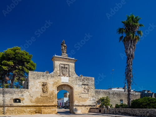 The small fortified village of Acaya, Lecce, Salento, Puglia, Italy. The large stone-paved square. The gateway to the city, with the large arch and the stone statue.