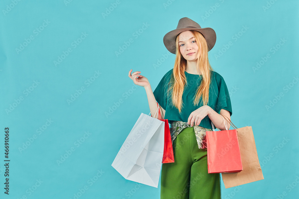 Happy young woman holding shopping bags staying. Pretty girl walk shopping center carry many packs good on blue background.