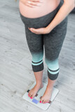 cropped view of blurred pregnant woman measuring body weight on floor scales