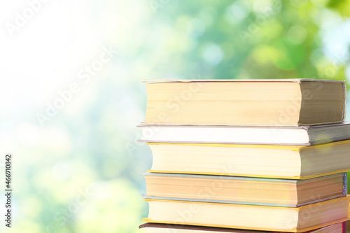 Stack of books on blurred background, space for text. Bokeh effect