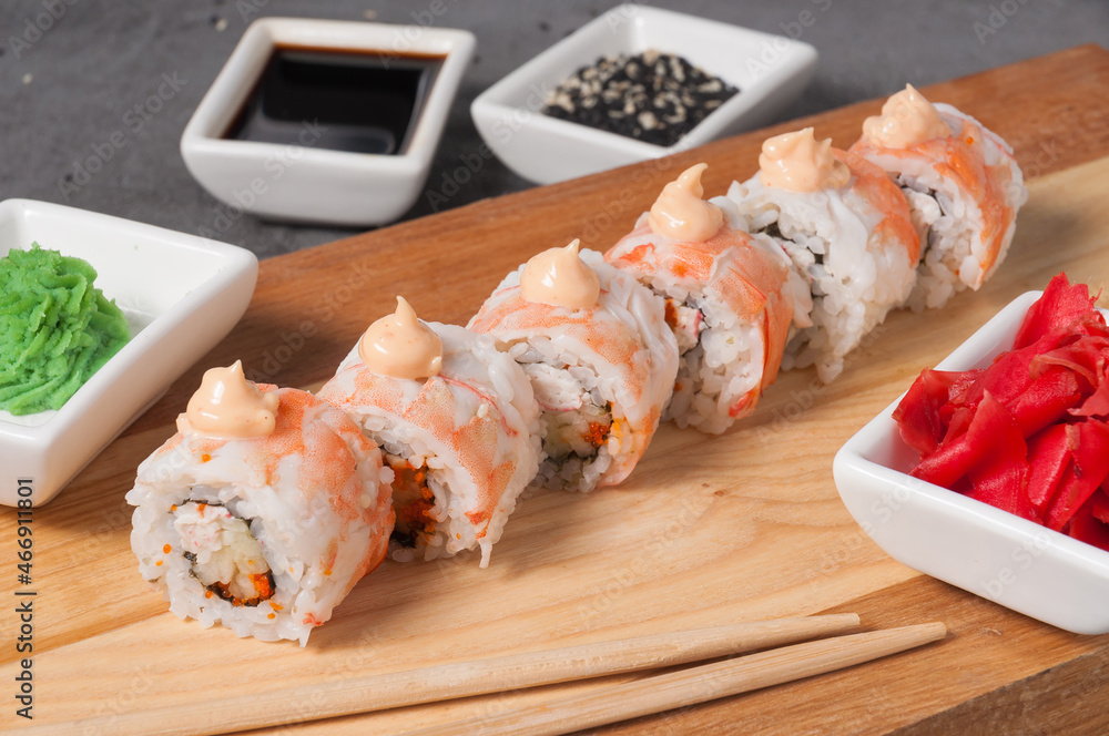sushi rolls with shrimp and crab on a wooden board