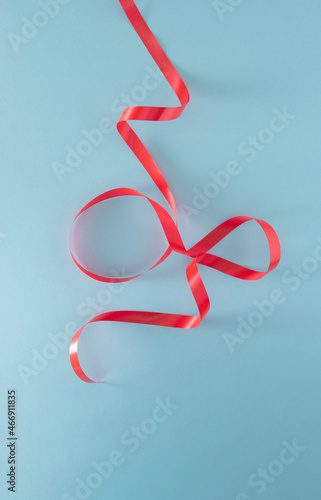 red gift wrapping tape in the shape of Christmas tree against pastel blue background. Minimalism