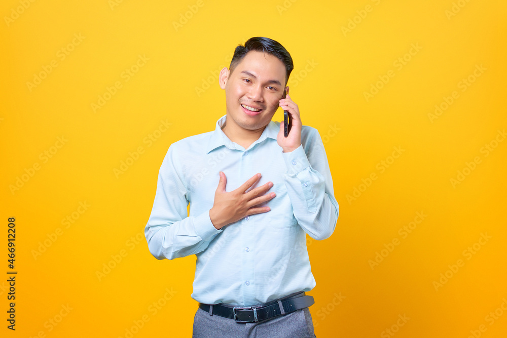 Happy young handsome businessman talking on smartphone and keeping other palms on a chest Happy young handsome businessman talking on smartphone and keeping other palms on a chest