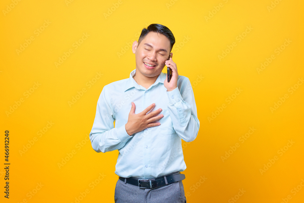 Happy young handsome businessman talking on smartphone and keeping other palms on a chest Happy young handsome businessman talking on smartphone and keeping other palms on a chest