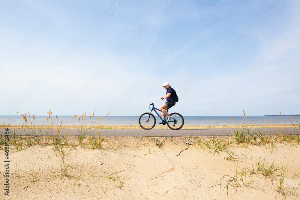 A cyclist rides on an asphalt path along the sea