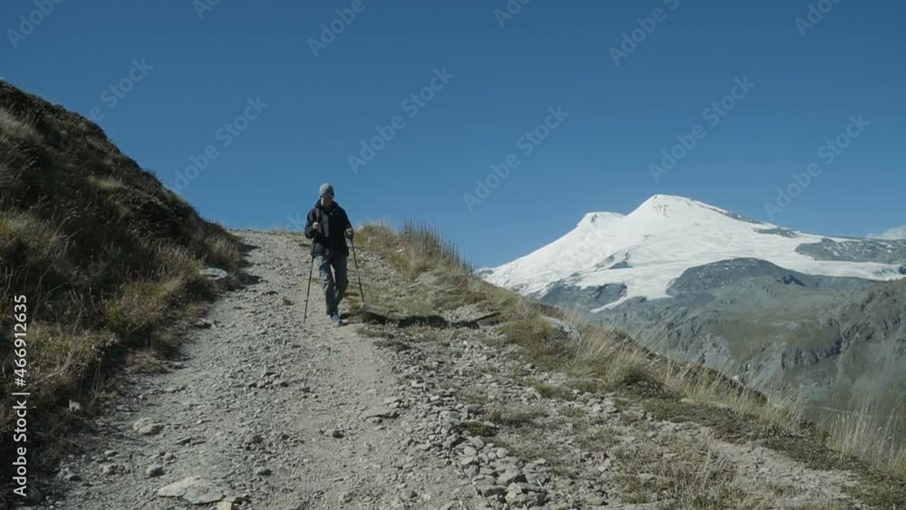 Slow motion - Hiker woman walking the edge of the canyon with Elbrus mountain background. People Hiking Mountains. Caucasus Mountains, Russia. Active Lifestyle Adventure Concept Slow motion - Hiker woman walking the edge of the canyon with Elbrus mountain background. People Hiking Mountains. Caucasus Mountains, Russia. Active Lifestyle Adventure Concept