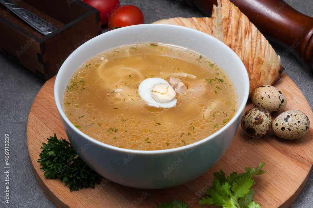 chicken soup with noodles and quail egg on a wooden board chicken soup with noodles and quail egg on a wooden board
