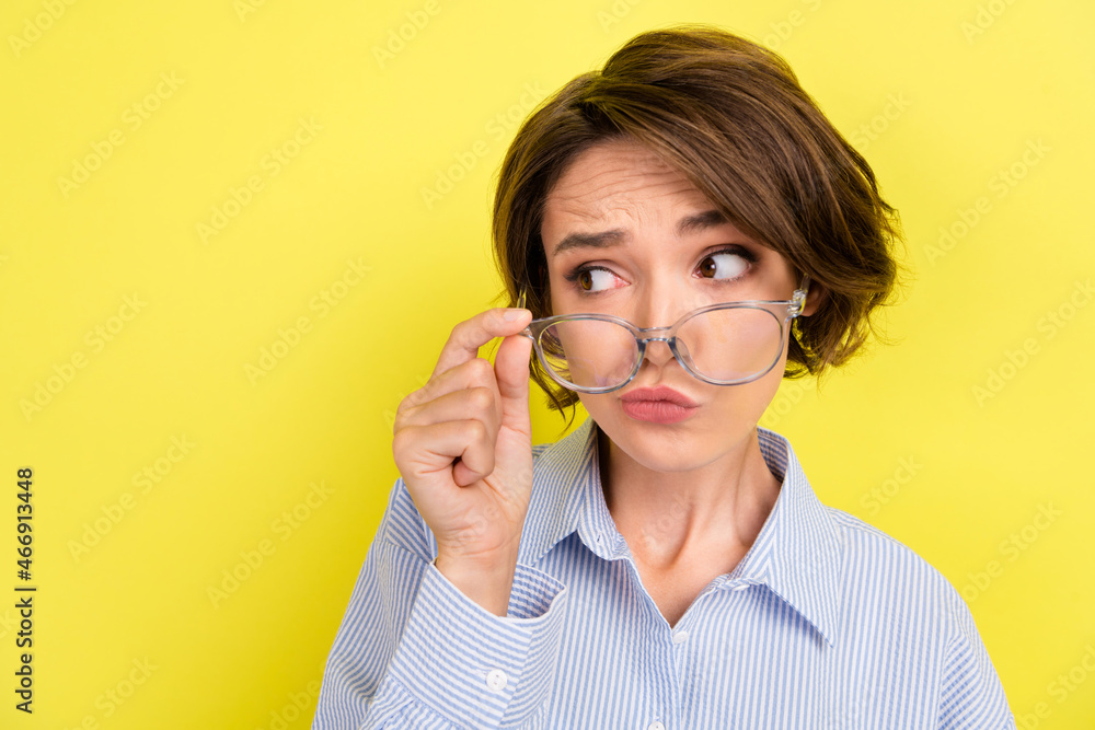 Photo of young woman hand touch glasses look empty space spy suspicious isolated over yellow color background Photo of young woman hand touch glasses look empty space spy suspicious isolated over yellow color background