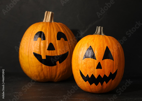 Pumpkins with drawn spooky faces on dark background. Halloween celebration