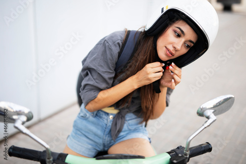 Beautiful woman getting ready for a ride on scooter. Beautiful happy lady having fun outdoors..