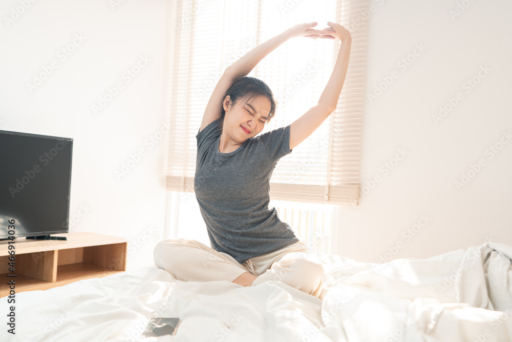 Bedroom concept in the morning the pretty girl just waking up and stretching her body on the brown wooden bed Bedroom concept in the morning the pretty girl just waking up and stretching her body on the brown wooden bed