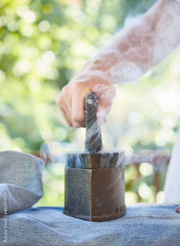 Woman ironing jeans at home on sunlit terrace with an ancient iron. Hot, vintage old iron with coal, selective focus.