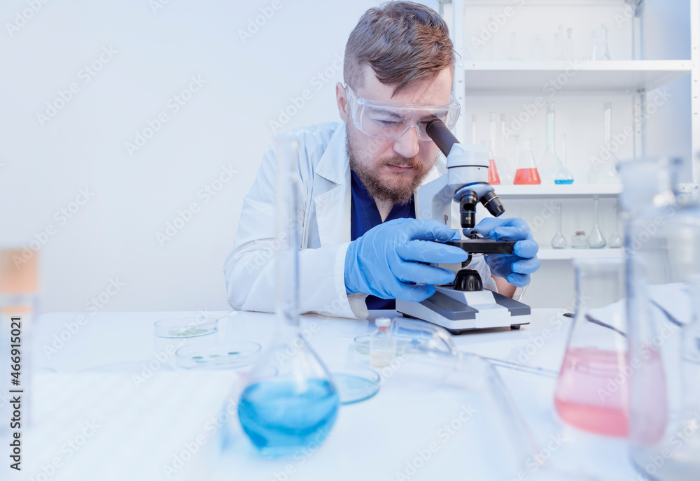 Doctor make a DNA test with samples in laboratory, looking at microscope Doctor make a DNA test with samples in laboratory, looking at microscope
