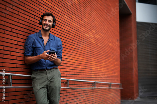 Young man listening to music. Urban fashion man with headphones enjoying the city.