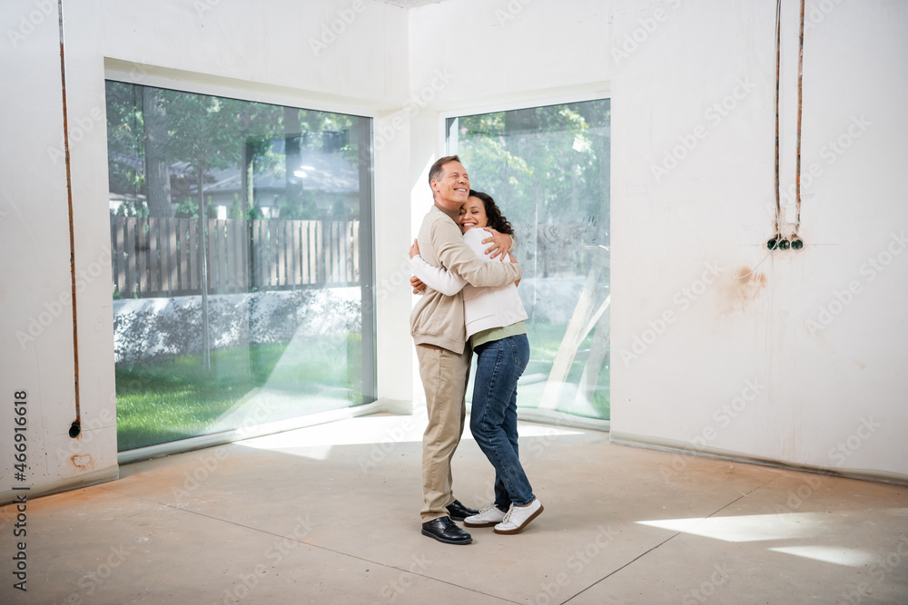 happy man hugging pleased african american wife in new house happy man hugging pleased african american wife in new house