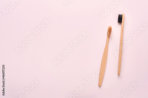 Teeth hygiene and oral dental care products on pink color background with copy space. Eco-friendly bamboo toothbrushes and cotton flowers. Flat lay  top view composition  mockup. Morning concept.