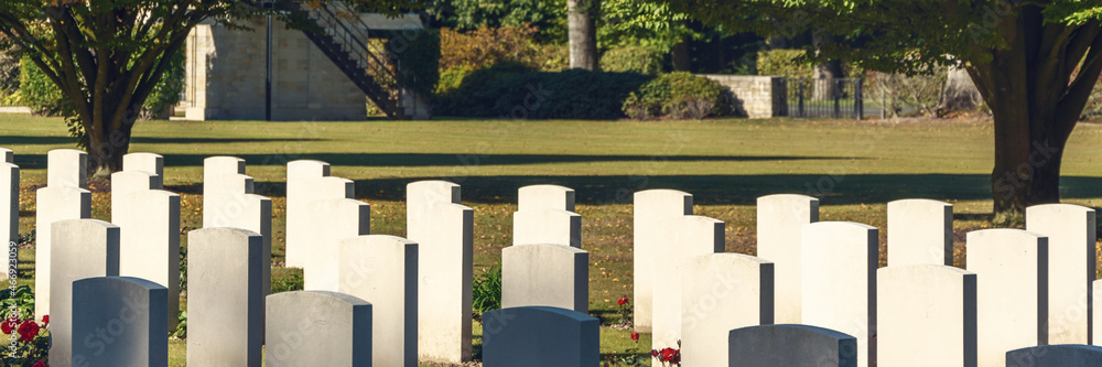cemetery with white graves on green grass in the autumn sun panorama