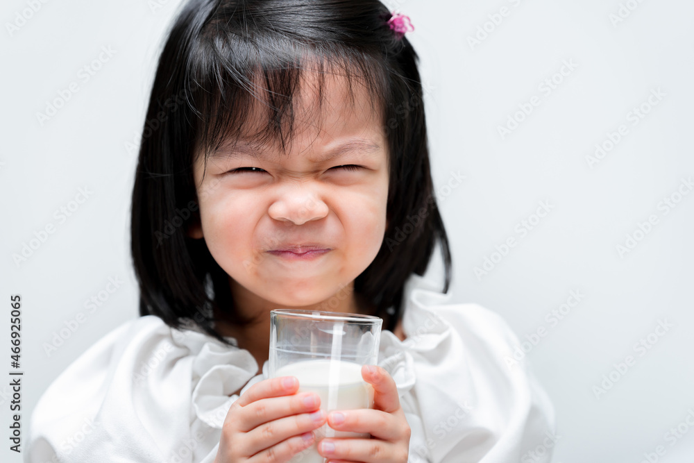 Cute girl is drinking milk from a glass. Children like to drink milk. A 4 year old girl. Isolated white background. Cute girl is drinking milk from a glass. Children like to drink milk. A 4 year old girl. Isolated white background.