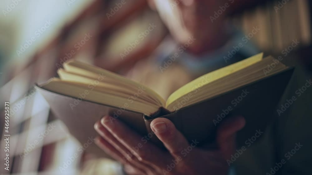 Senior man reading a book in public library, turning pages, doing research
