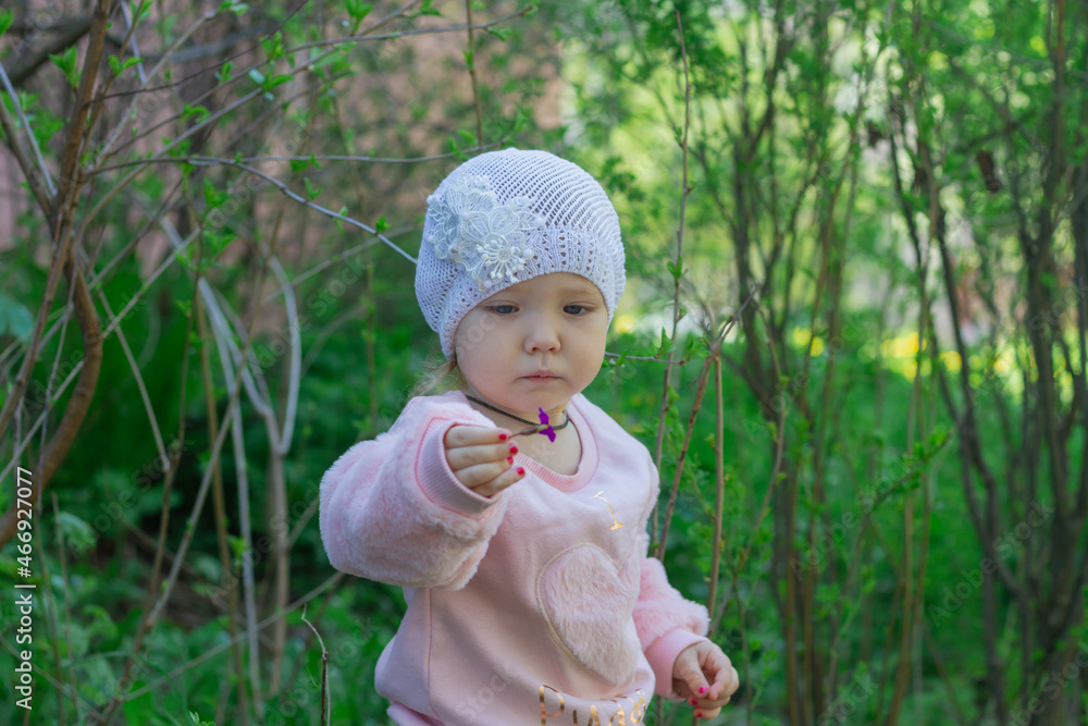 Cute little gentle girl 2 years old in a pink soft jacket walks in the park Cute little gentle girl 2 years old in a pink soft jacket walks in the park